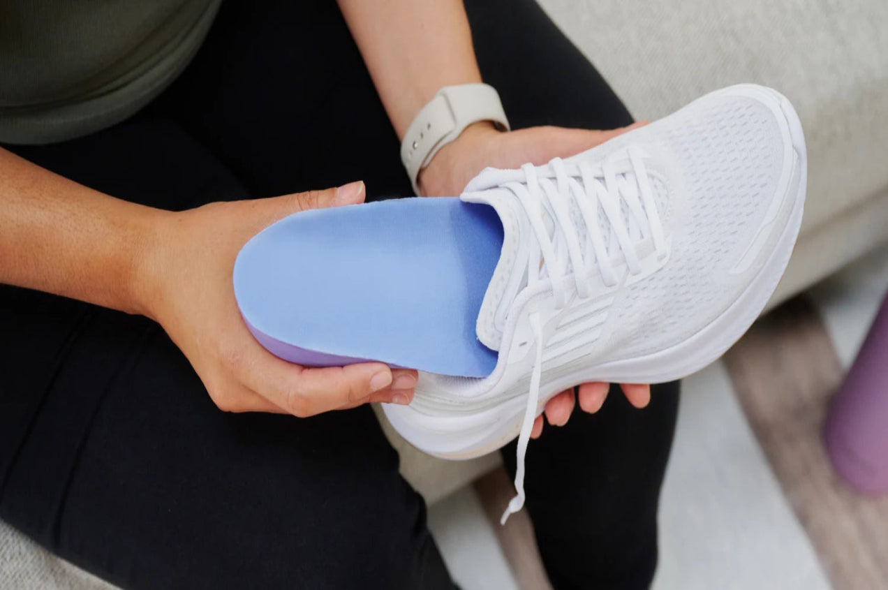 Woman inserting an insole into her shoe.